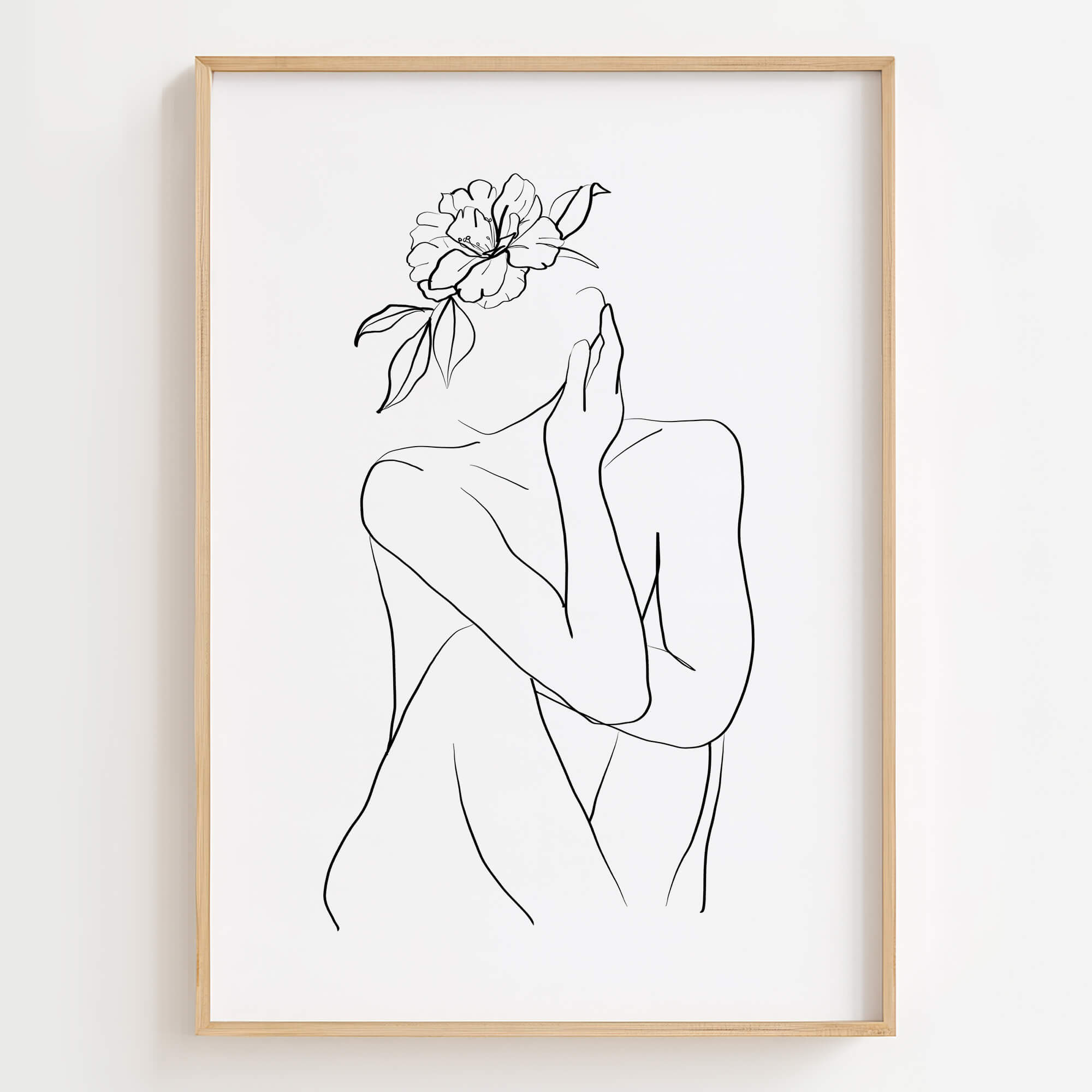 Abstract minimalist black line art print of a woman's body in a seated pose with a single flower on her head, in a wooden frame.