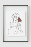 Close-up view of a woman holding a rose art print, highlighting the delicate line work and graceful details.